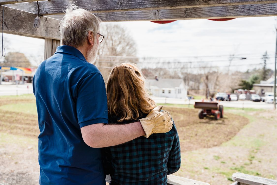 Older couple embracing while looking out over their American farmland